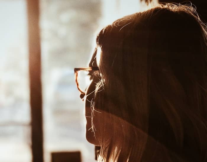 Eine junge Frau sieht sorgenvoll aus einem Fenster