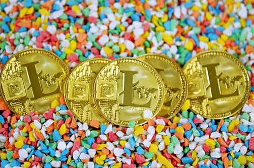 Fünf Litecoin Münzen liegen präsentiert auf bunten Dekosteinen