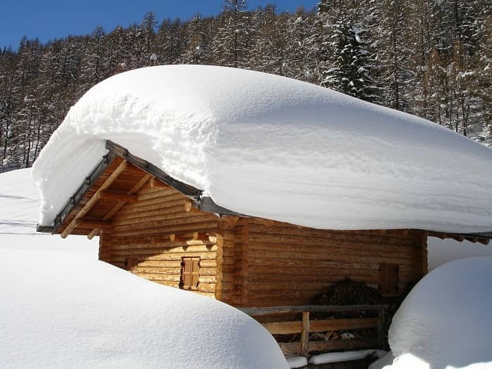 Eine hoch eingeschneite Hütte steht in der Sonne