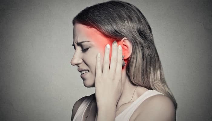 Frau die unter Schmerzen leidet und sich an das Ohr fasst