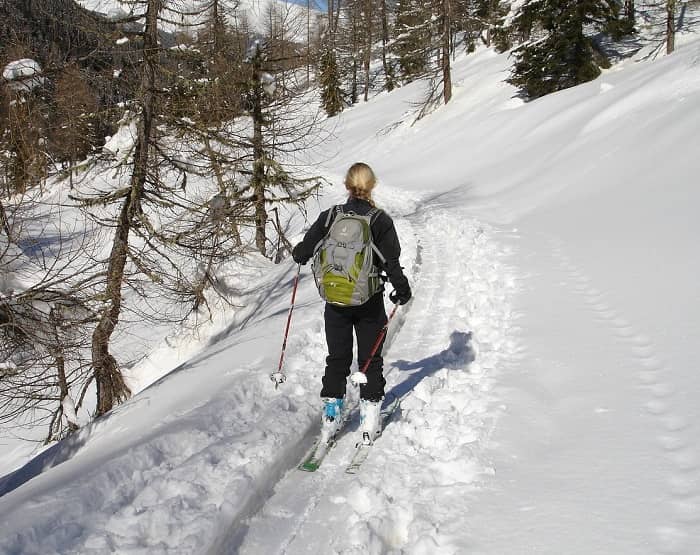 Eine Frau fährt mit Skiern einen schneebedeckten Weg entlang