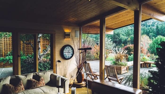 Ein gemütlicher überdachter Terrassenraum mit großen Fenstern und viel Holz