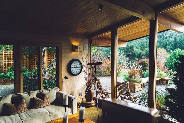 Ein gemütlicher überdachter Terrassenraum mit großen Fenstern und viel Holz