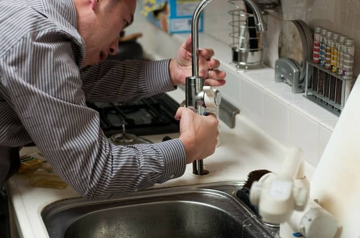 Ein Handwerker befestigt einen Wasserhahn in der Küche