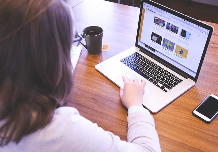 Eine Frau sitzt mit einer Tasse Tee am Laptop