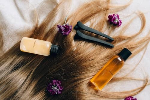 Lange Haare liegen mit einigen Blüten und shampoos auf einem Tisch