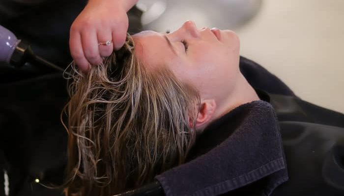 Eine Frau sitzt beim Frisör und bekommt die Haare gewaschen