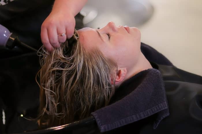 Eine Frau sitzt beim Frisör und bekommt die Haare gewaschen