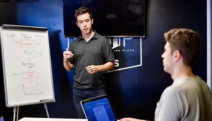 Ein Mann unterichtet einen anderen Mann, stehend vor einem Flipchart