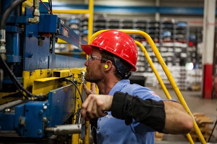 Ein Arbeiter steht bei einer sehr großen Maschine und bedient sie gerade