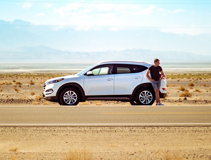 Ein Mann steht bei einem Auto, in freier wüstenähnlicher Landschaft