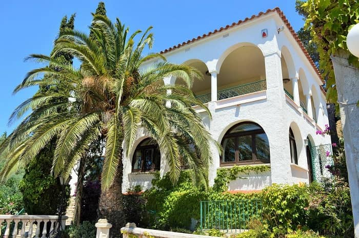 Eine schöne Villa mit großzügigen Rundbögen und Säulen in einem Palmengarten