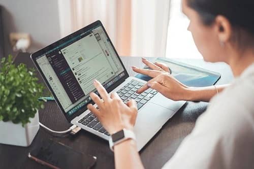 Eine Frau tippt auf einem Laptop einen Text