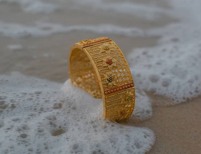 Ein goldener Ring steht im Sand und wird von Meerwasser umspült