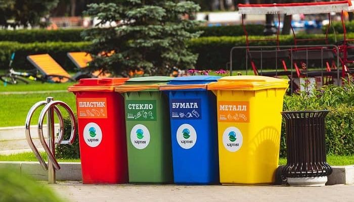 Vier unterschiedlich farbige Mülltonnen stehen auf einem Platz