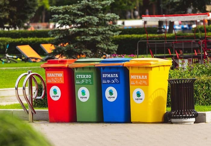 Vier unterschiedlich farbige Mülltonnen stehen auf einem Platz