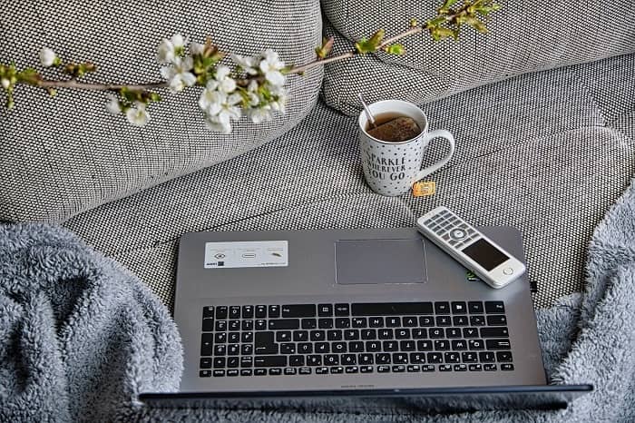 Ein Laptop, ein Telefon und eine Tasse Tee stehen auf einem Sofa