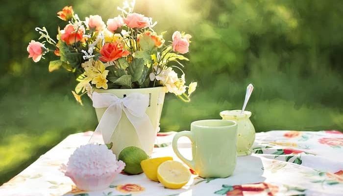 Eine Vase mit bunten Blumen steht auf einem gedeckten Tisch, im Sonnenschein