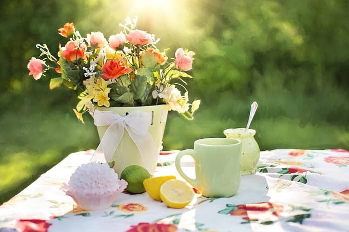 Eine Vase mit bunten Blumen steht auf einem gedeckten Tisch, im Sonnenschein