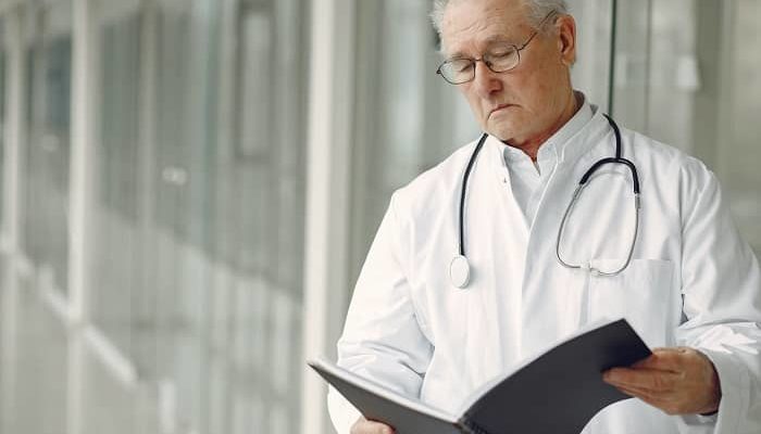 Ein Arzt im weißen Kittel liest sich gerade einen Patientenbericht durch