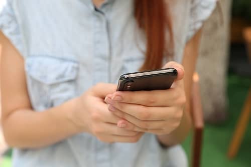 Eine Frau mit einem Smartphone in der Hand betrachtet den Bildschirm