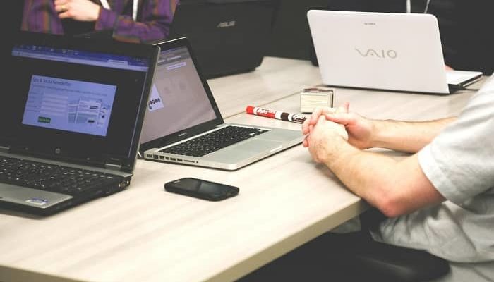 Ein Meeting mit 4 Männern, die alle einen Laptop auf dem Tisch stehen haben