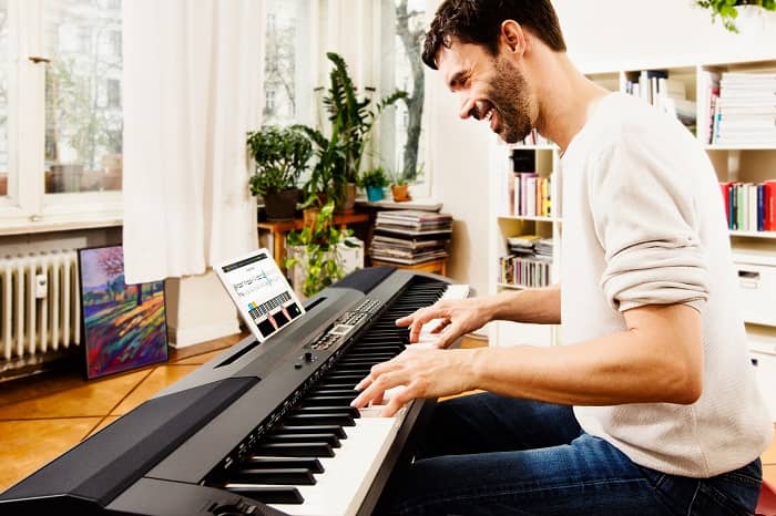 Mann spielt im Wohnzimmer Klavier