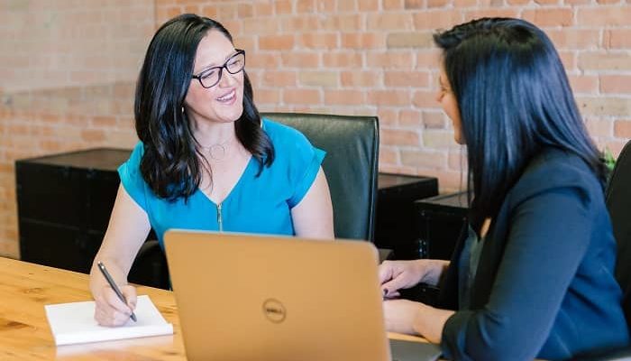 Zwei Frauen sitzen an einem Tisch und unterhalten sich