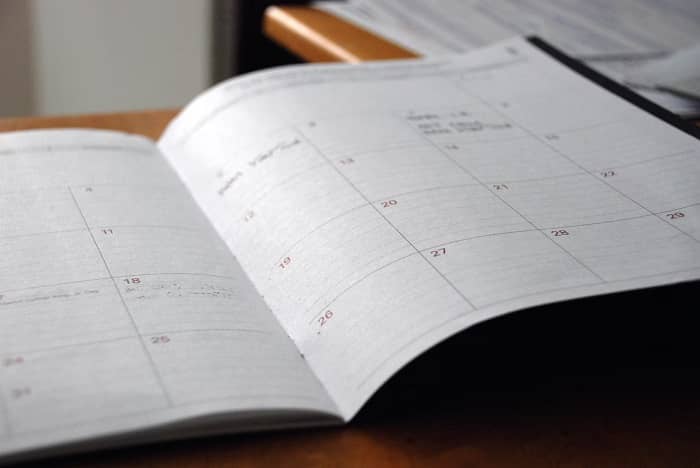 Ein Terminkalender mit eingetragenen Terminen liegt auf einem Schreibtisch