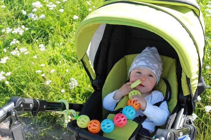 Auf einer Wiese steht ein Kinderwagen, in dem ein Baby sitzt