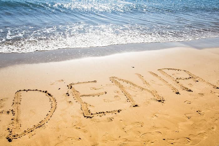 Das Wort Dénia in den sand am Strand geschrieben