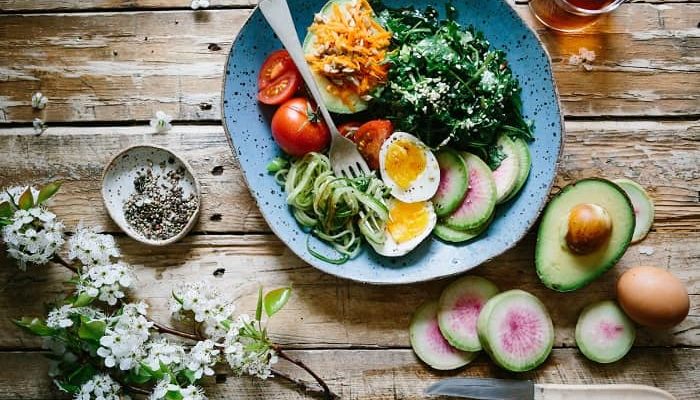 Eine Schüssel mit Gemüse und Salat, steht mit einer Gabel auf dem Tisch