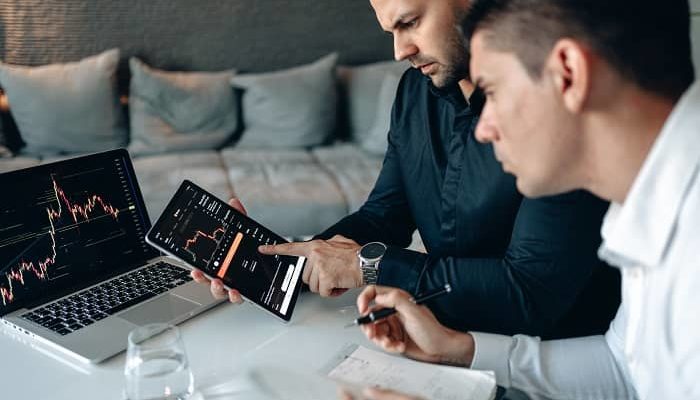 Zwei männer sitzen vor einem Laptop und betrachten einen Rankingverlauf