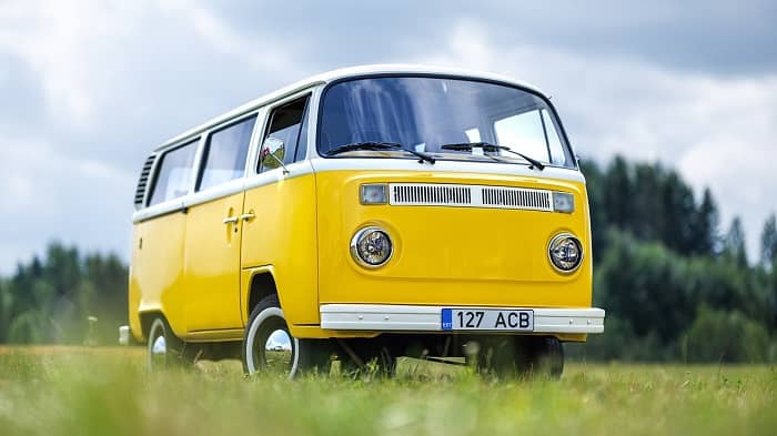 Ein alter gelb-weißer VW-Bus steht auf einer Wiese