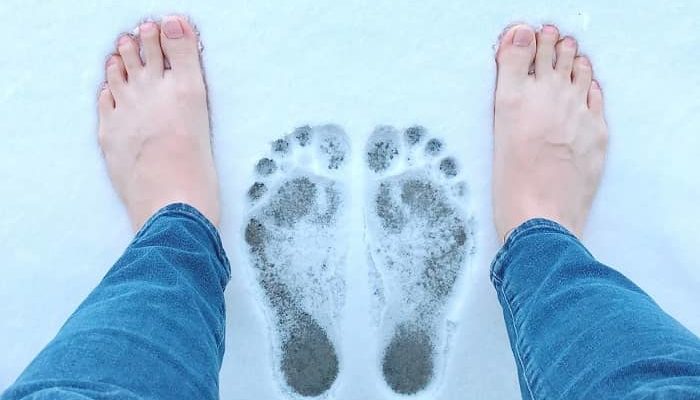 Ein Mann steht mit nackten Füßen im Schnee