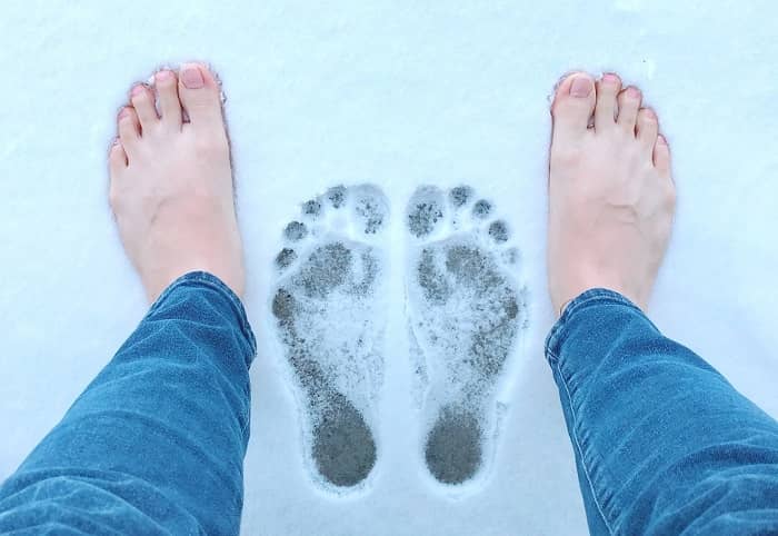 Ein Mann steht mit nackten Füßen im Schnee