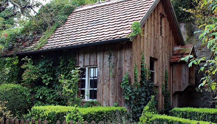Ein großes Holz Gartenhaus steht in einem schönen verwachsenen Garten