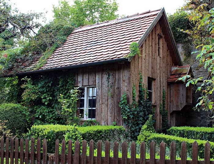 Ein großes Holz Gartenhaus steht in einem schönen verwachsenen Garten