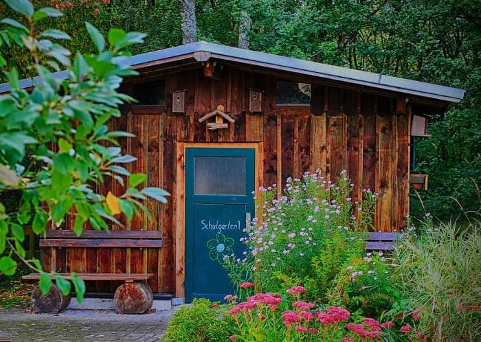 Ein Holz Gartenhaus mit grüner Eingangstür steht in einem Garten
