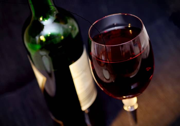 Eine Flasche und ein Glas mit Rotwein, stehen auf einem Tisch