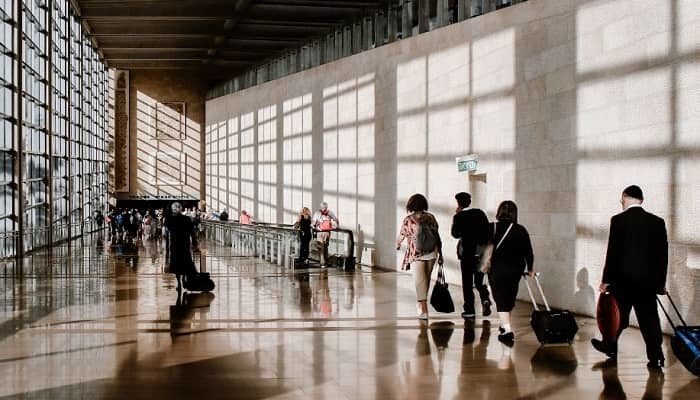 Reisende eilen durch eine große Halle am Flughafen