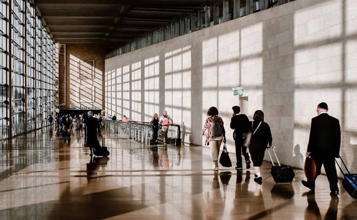 Reisende eilen durch eine große Halle am Flughafen
