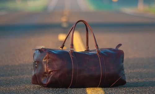Eine Reisetasche steht auf einer großen Landstrasse