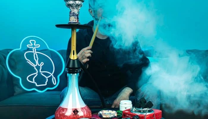 Ein Mann sitzt Shisha rauchend auf einem Sofa