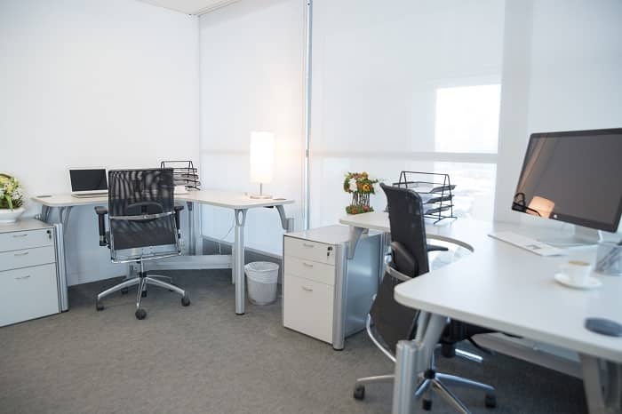 Ein helles Büro mit zwei Schreibtischen und zwei bürodrehstühlen