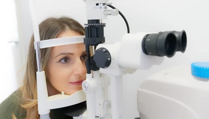 Eine Frau sitzt beim Augenarzt und macht einen Sehtest