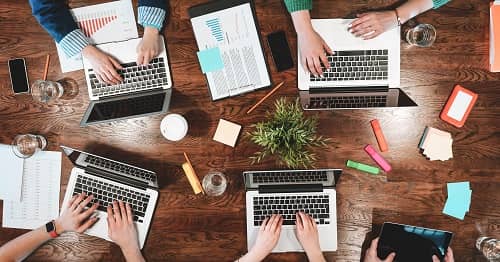 Vier Coworker sitzen an einem Tisch vor Ihren Laptops