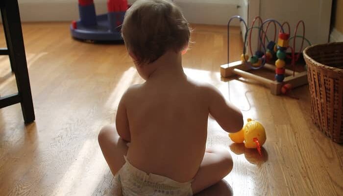 Ein Baby sitzt am Boden und spielt mit einem Spielzeug