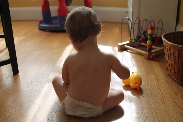 Ein Baby sitzt am Boden und spielt mit einem Spielzeug