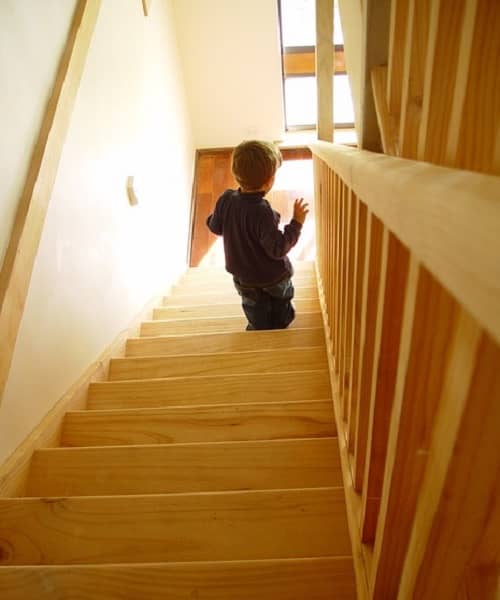 Ein kleines Kind geht eine steile Treppe, ohne sich festzuhalten, hinunter